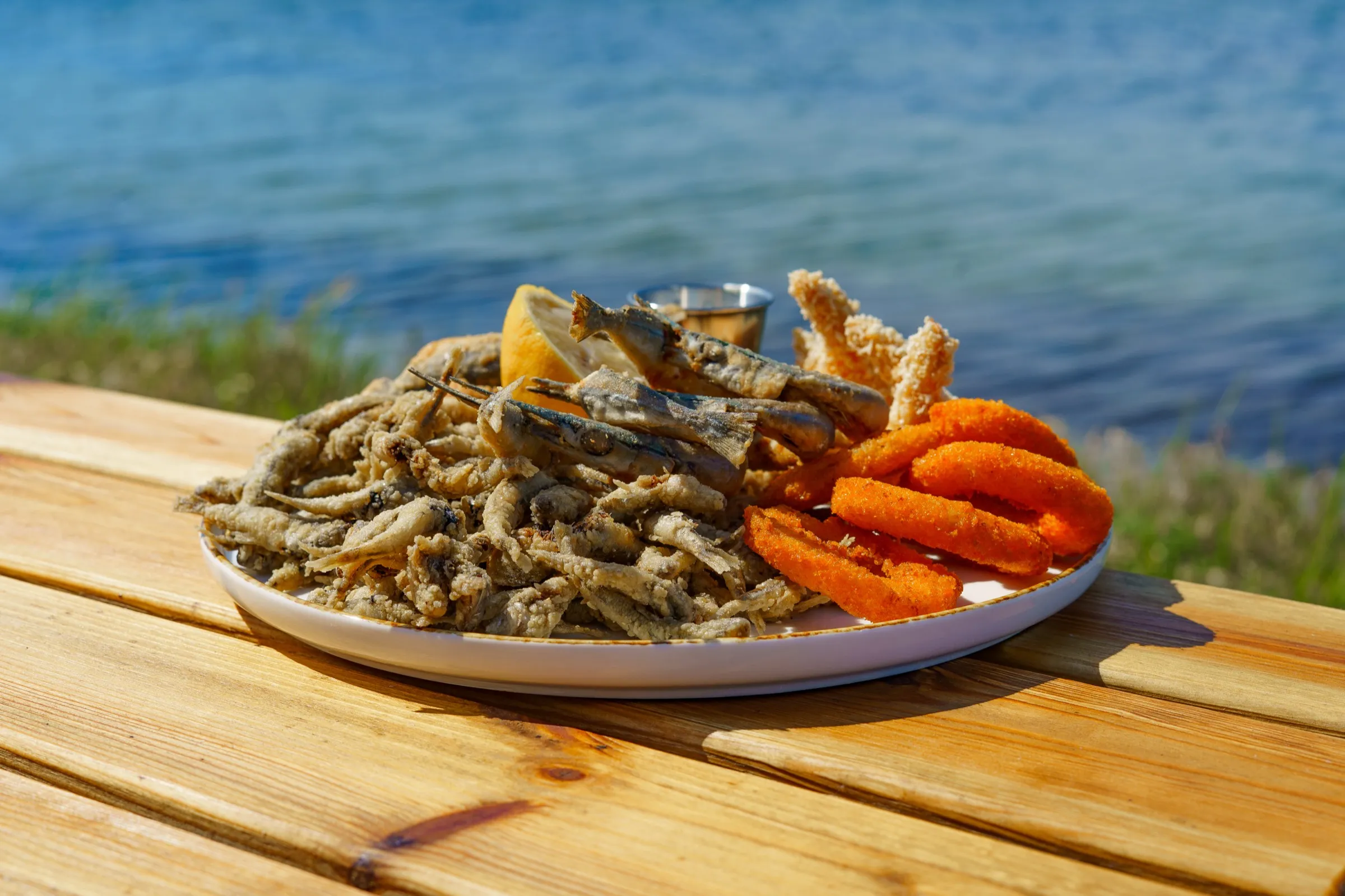 Тарілка з локальних смажених морепродуктів біля води